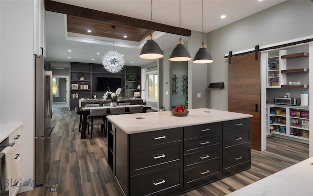 kitchen featuring dark hardwood / wood-style flooring, hanging light fixtures, a tray ceiling, and a barn door