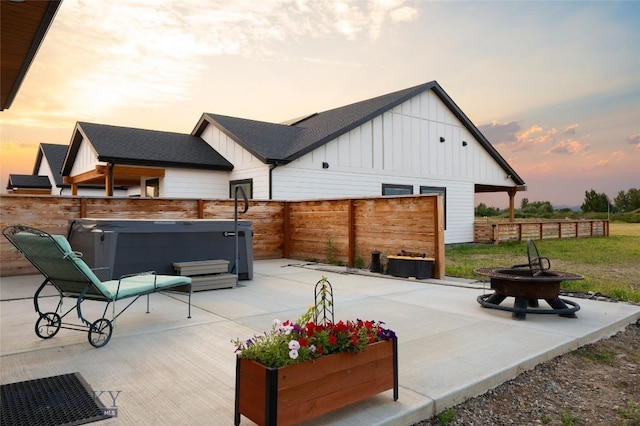 patio terrace at dusk with an outdoor fire pit and a hot tub