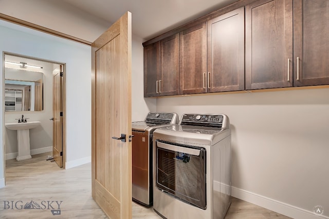 laundry area with light hardwood / wood-style floors, cabinets, and washer and dryer