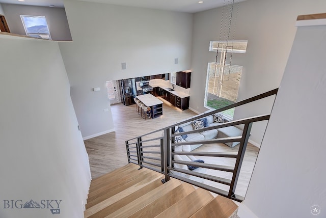 stairs with light wood-type flooring and a high ceiling