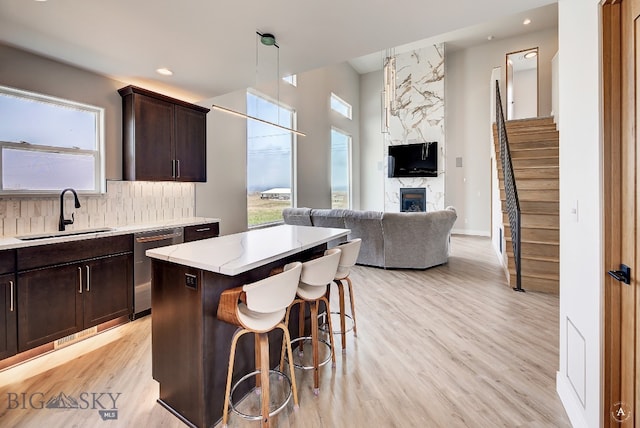 kitchen featuring light hardwood / wood-style flooring, sink, a fireplace, decorative light fixtures, and a kitchen island