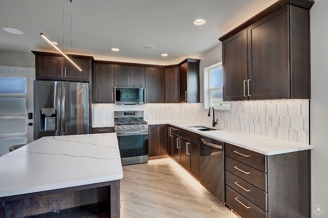 kitchen with light hardwood / wood-style flooring, stainless steel appliances, tasteful backsplash, sink, and light stone counters