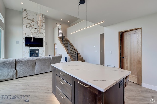 kitchen featuring light hardwood / wood-style flooring, a premium fireplace, dark brown cabinetry, and plenty of natural light