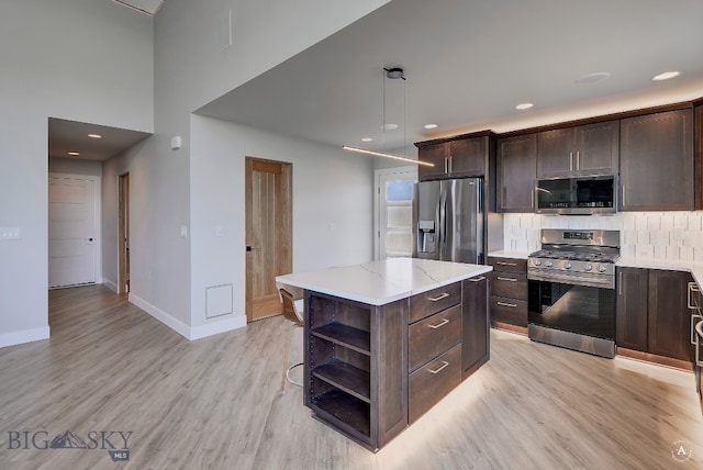 kitchen with a center island, backsplash, stainless steel appliances, light hardwood / wood-style floors, and decorative light fixtures