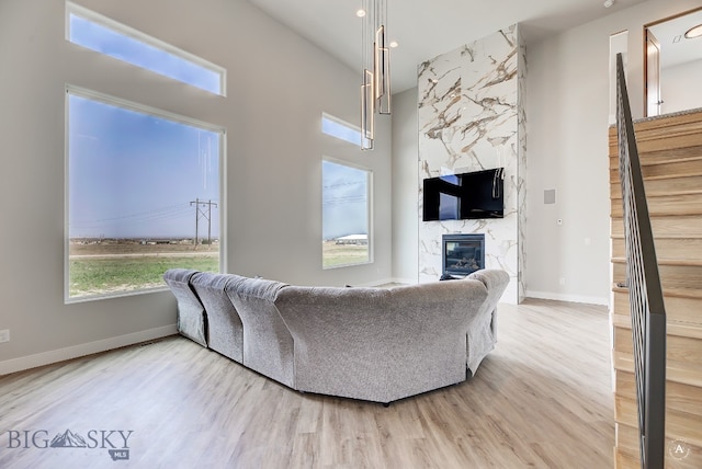 living room with a high ceiling, hardwood / wood-style flooring, and a high end fireplace