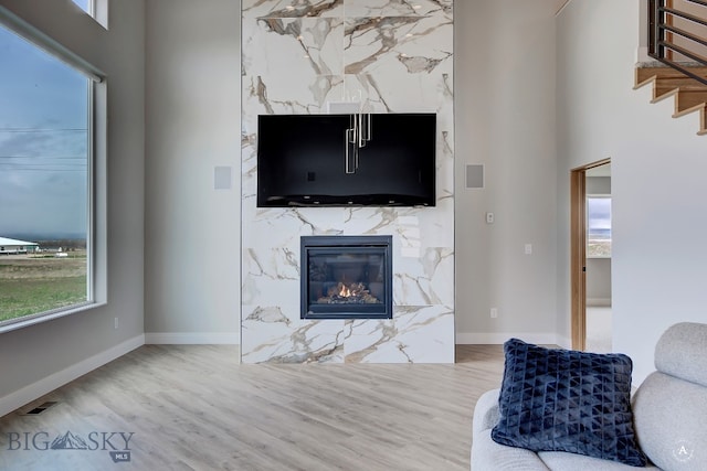 living room featuring a fireplace, hardwood / wood-style flooring, and a towering ceiling