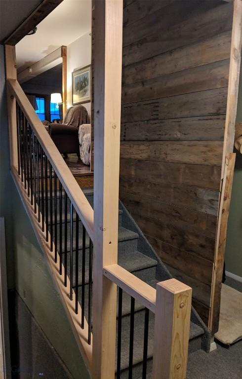 stairs with carpet and wood walls