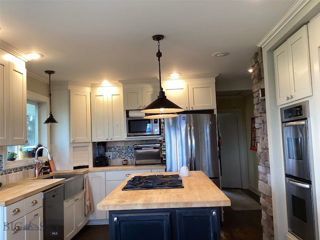 kitchen with stainless steel appliances, a center island, butcher block counters, and hanging light fixtures