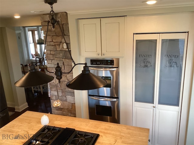 kitchen featuring crown molding, stainless steel double oven, white cabinets, gas cooktop, and butcher block countertops