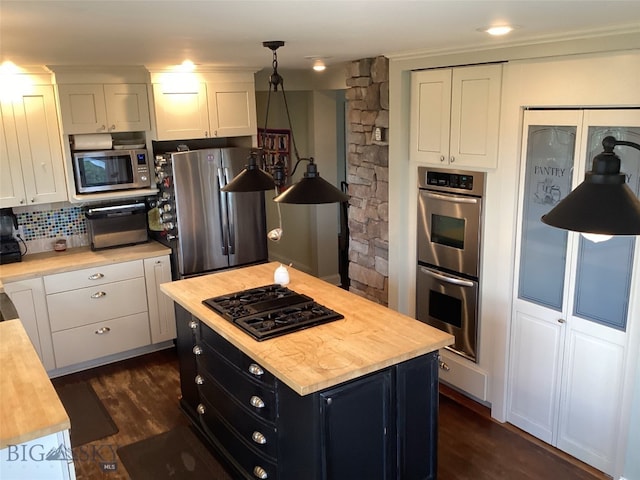 kitchen featuring appliances with stainless steel finishes, a kitchen island, white cabinetry, and pendant lighting