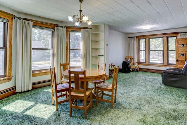 carpeted dining area featuring an inviting chandelier, a healthy amount of sunlight, and a baseboard heating unit