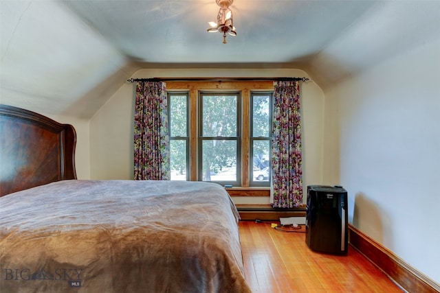 bedroom featuring lofted ceiling, multiple windows, and light hardwood / wood-style flooring