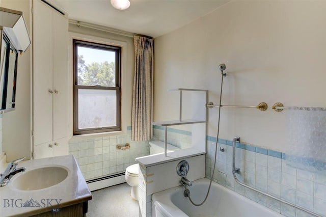 full bathroom featuring toilet, a bathing tub, baseboard heating, vanity, and tile walls