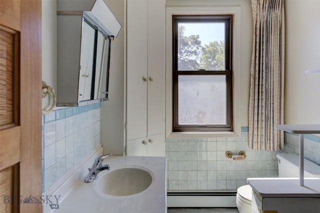 bathroom with a baseboard heating unit, a sink, tile walls, and toilet