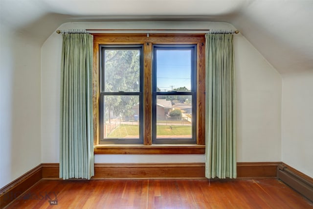 bonus room featuring a baseboard radiator, vaulted ceiling, wood-type flooring, and plenty of natural light