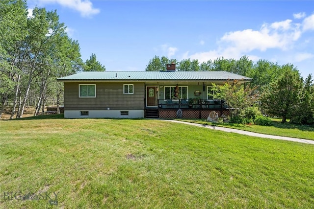 back of house with covered porch, a chimney, a yard, and metal roof