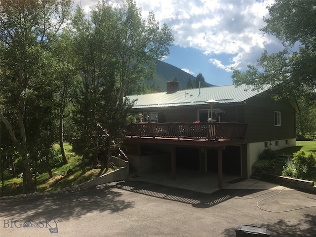 rear view of property with a patio and a deck with mountain view