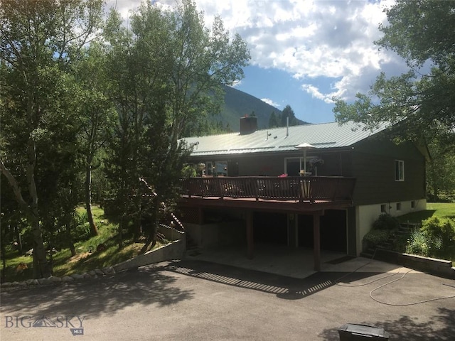 rear view of house featuring a deck with mountain view and metal roof