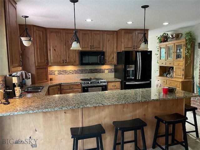 kitchen with a peninsula, pendant lighting, brown cabinetry, and black appliances