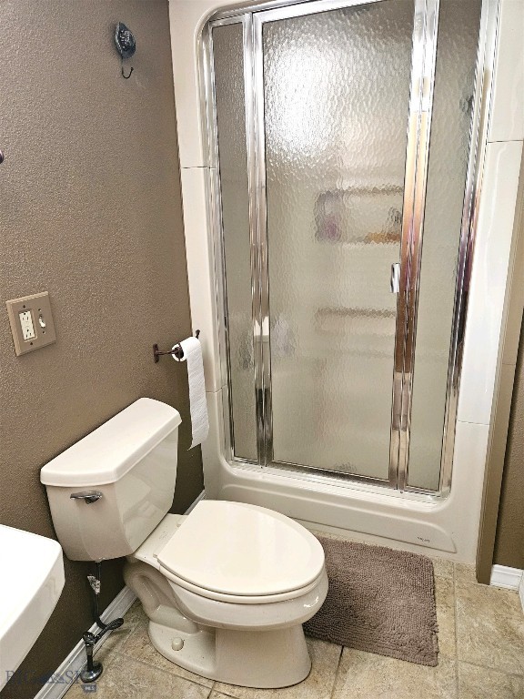 bathroom with baseboards, a stall shower, and toilet