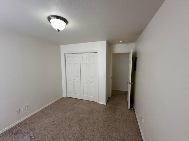 unfurnished bedroom with carpet, a textured ceiling, and a closet