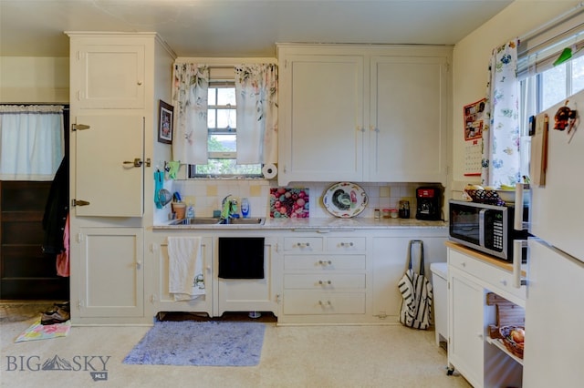 kitchen featuring sink, decorative backsplash, white cabinets, and a healthy amount of sunlight