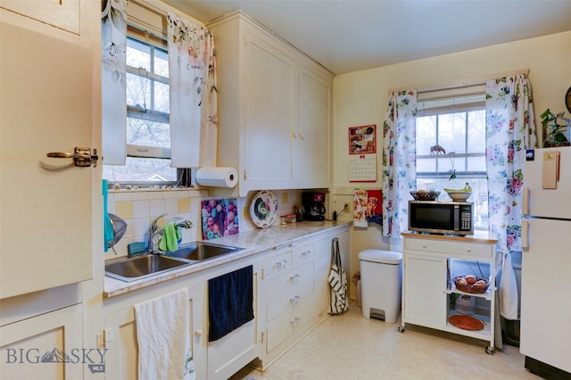 kitchen featuring sink, white cabinetry, white refrigerator, and a healthy amount of sunlight