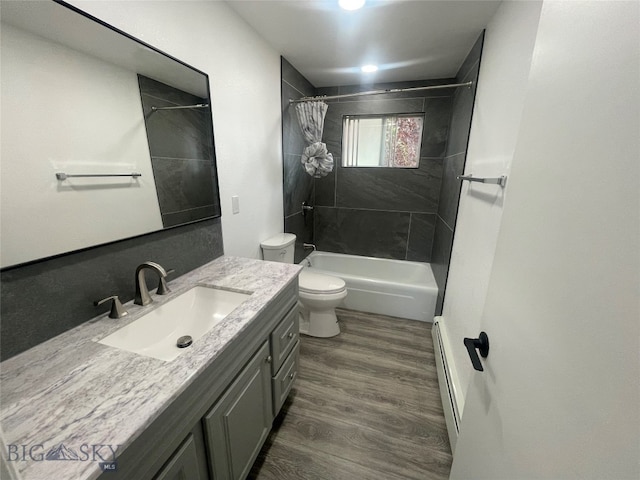 full bathroom with vanity, a baseboard radiator, hardwood / wood-style floors, toilet, and shower / bath combo