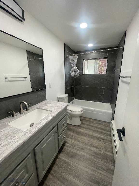 full bathroom with a baseboard heating unit, toilet, wood-type flooring, shower / bath combo with shower curtain, and vanity