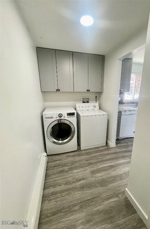 laundry room featuring separate washer and dryer, cabinets, and hardwood / wood-style floors