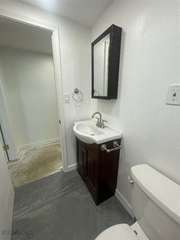 bathroom with vanity, toilet, and concrete flooring