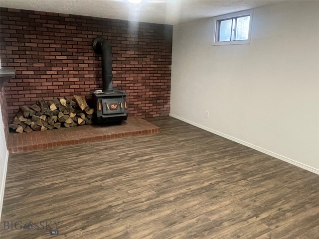 basement with a textured ceiling, hardwood / wood-style flooring, and a wood stove