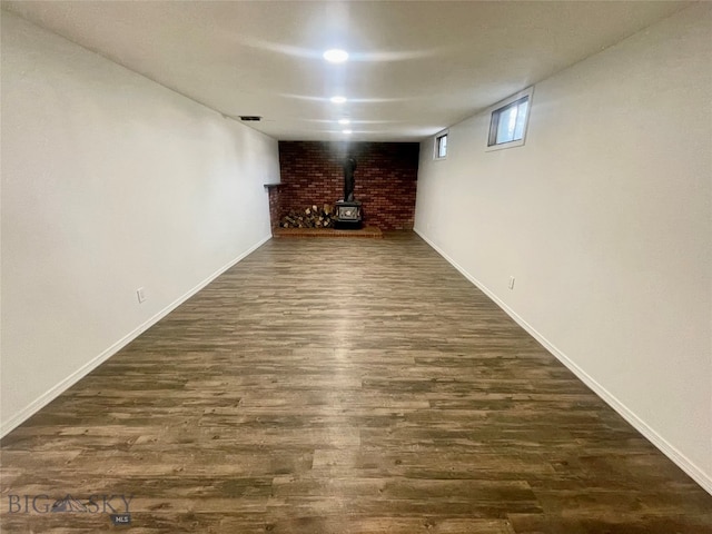 basement with a wood stove and hardwood / wood-style floors