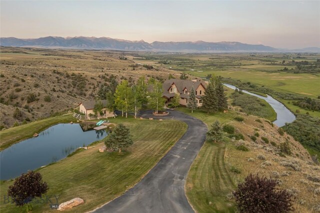 aerial view at dusk featuring a mountain view and a rural view