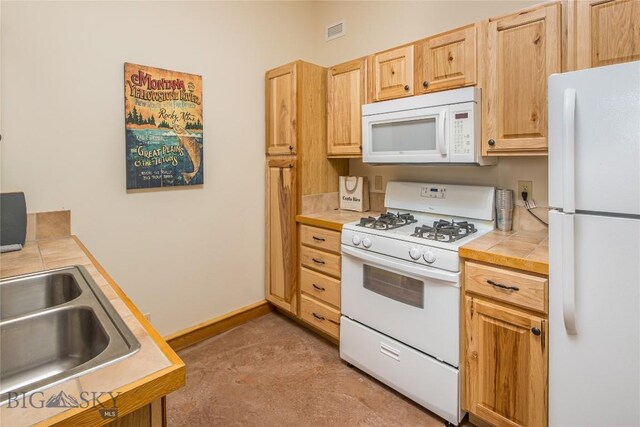 kitchen featuring tile counters, light brown cabinets, white appliances, and sink