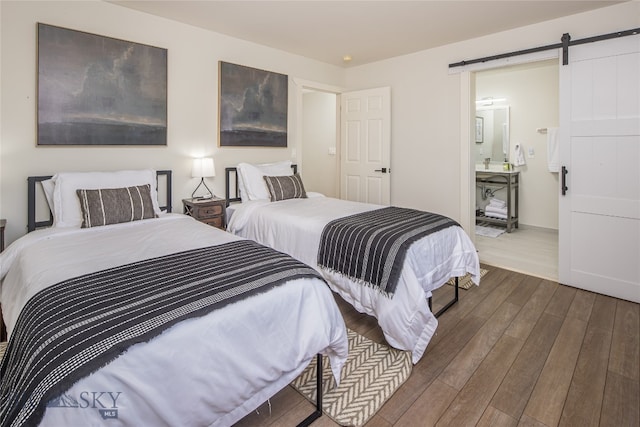 bedroom featuring connected bathroom, hardwood / wood-style floors, and a barn door