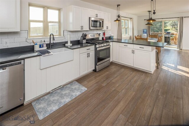 kitchen featuring decorative backsplash, dark wood-type flooring, kitchen peninsula, and stainless steel appliances