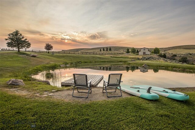 exterior space featuring a water view, a lawn, and a rural view