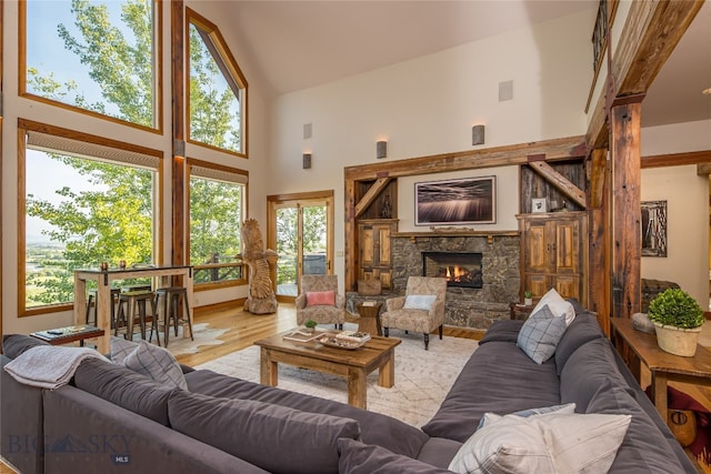 living room featuring a stone fireplace, light hardwood / wood-style floors, and high vaulted ceiling