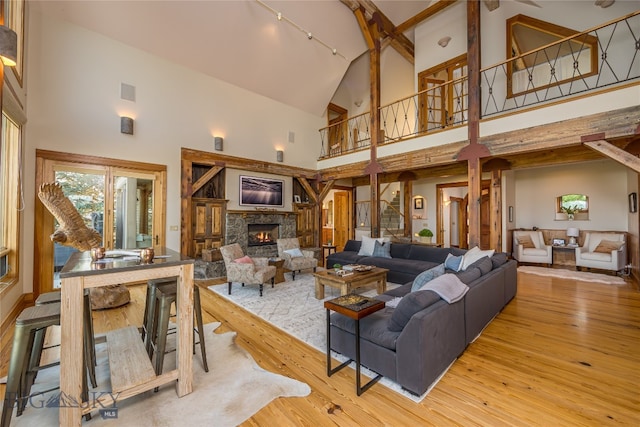 living room featuring a stone fireplace, light wood-type flooring, and high vaulted ceiling