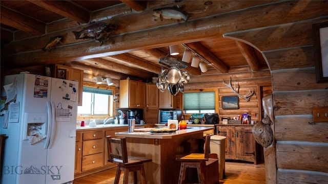 kitchen featuring log walls, a kitchen island, white fridge with ice dispenser, beam ceiling, and light hardwood / wood-style floors