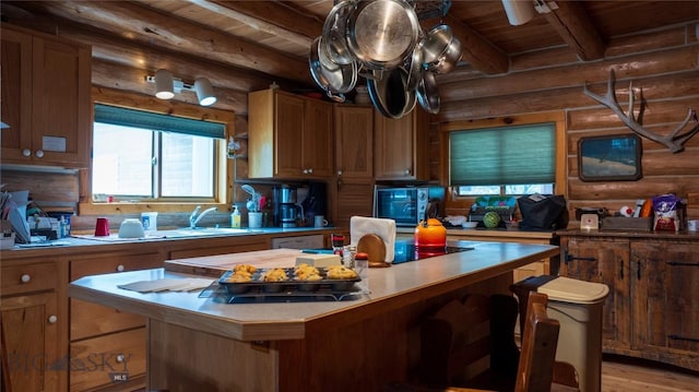 kitchen featuring beamed ceiling, sink, a center island, wood ceiling, and light wood-type flooring