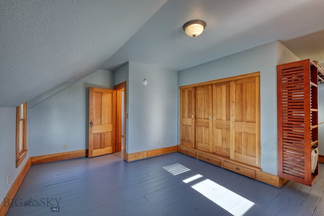 bonus room featuring lofted ceiling, dark hardwood / wood-style flooring, and a textured ceiling