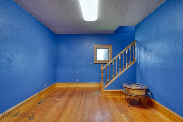 unfurnished room with a textured ceiling and hardwood / wood-style floors