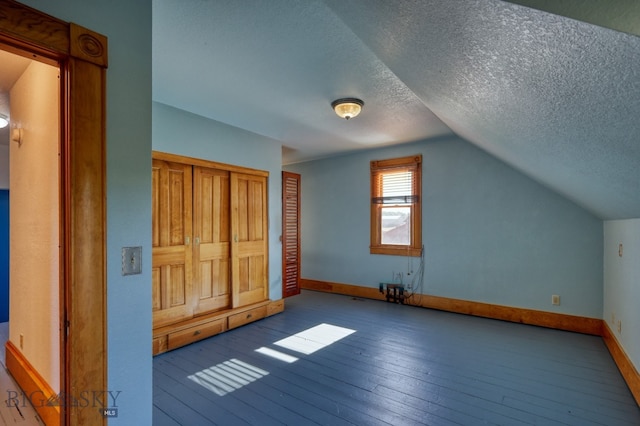 bonus room featuring wood-type flooring, vaulted ceiling, and a textured ceiling