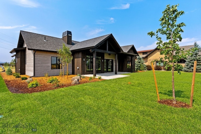 rear view of property featuring a chimney and a lawn