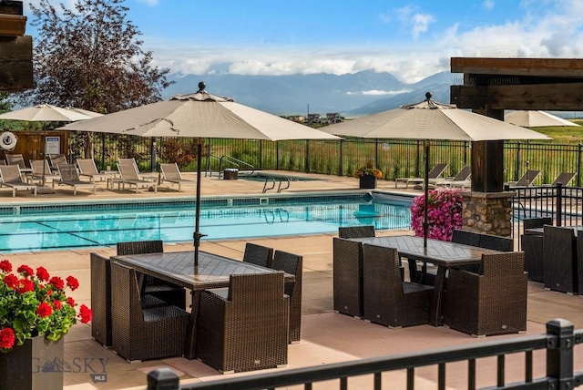 community pool featuring a patio, fence, and a mountain view