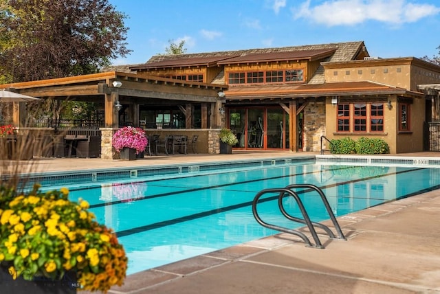 community pool with a patio area and outdoor dry bar