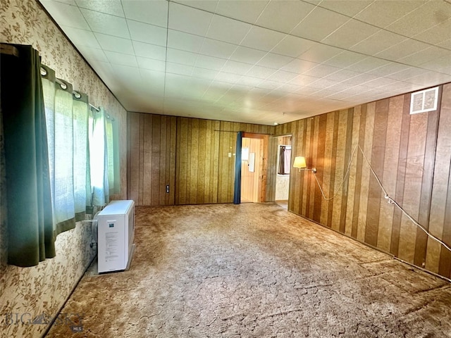 unfurnished room featuring wooden walls and carpet