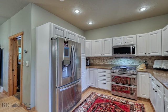 83 W Pine Cone Ter, Big Sky, MT 59716 - kitchen with stainless steel appliances, light wood finished floors, white cabinets, tasteful backsplash, and recessed lighting